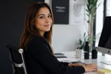 Professional woman in black blazer sitting at desk with computer
